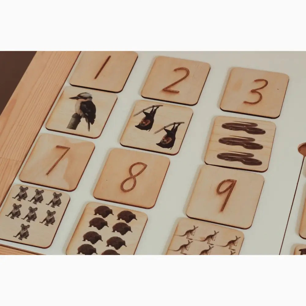 Wooden number and animal counting tiles arranged in a grid pattern.