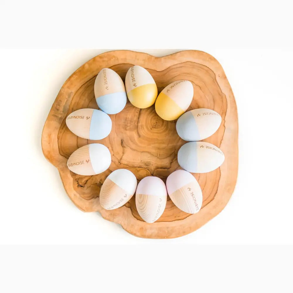 Wooden bowl containing a circular arrangement of pastel-colored eggs.