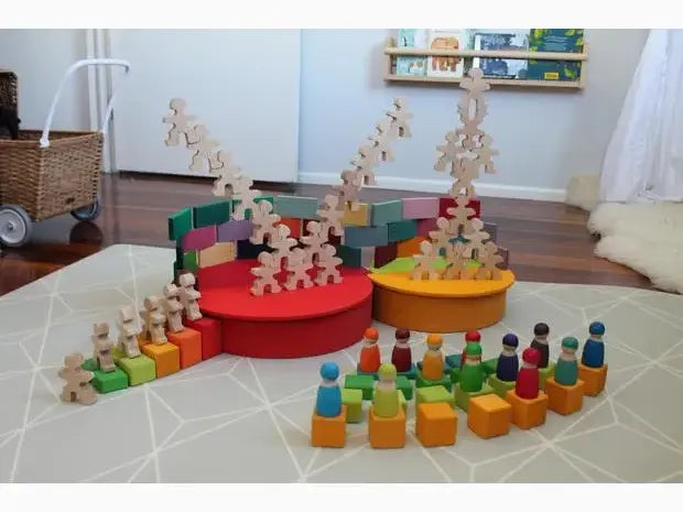 Colorful wooden toy set with blocks, figurines, and circular platforms arranged on a rug.