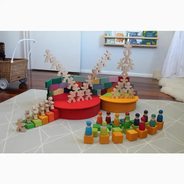 Colorful wooden toy set with blocks, figurines, and circular platforms arranged on a rug.