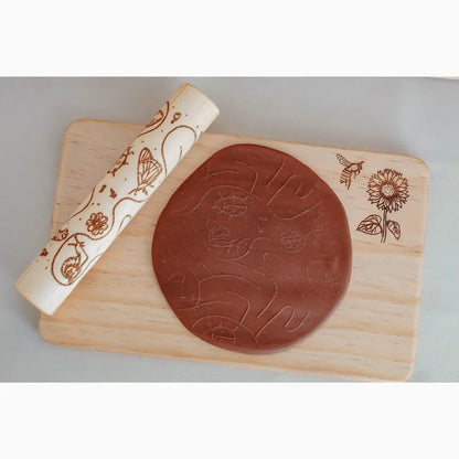 Circular disc of brown clay or dough with embossed designs on a wooden board.