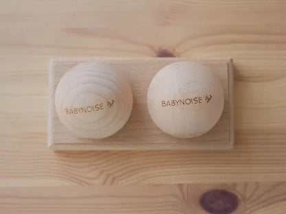 Two white circular devices labeled ’BABYNOISE’ on a wooden surface.