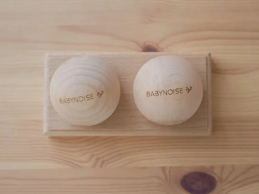 Two white circular devices labeled ’BABYNOISE’ on a wooden surface.