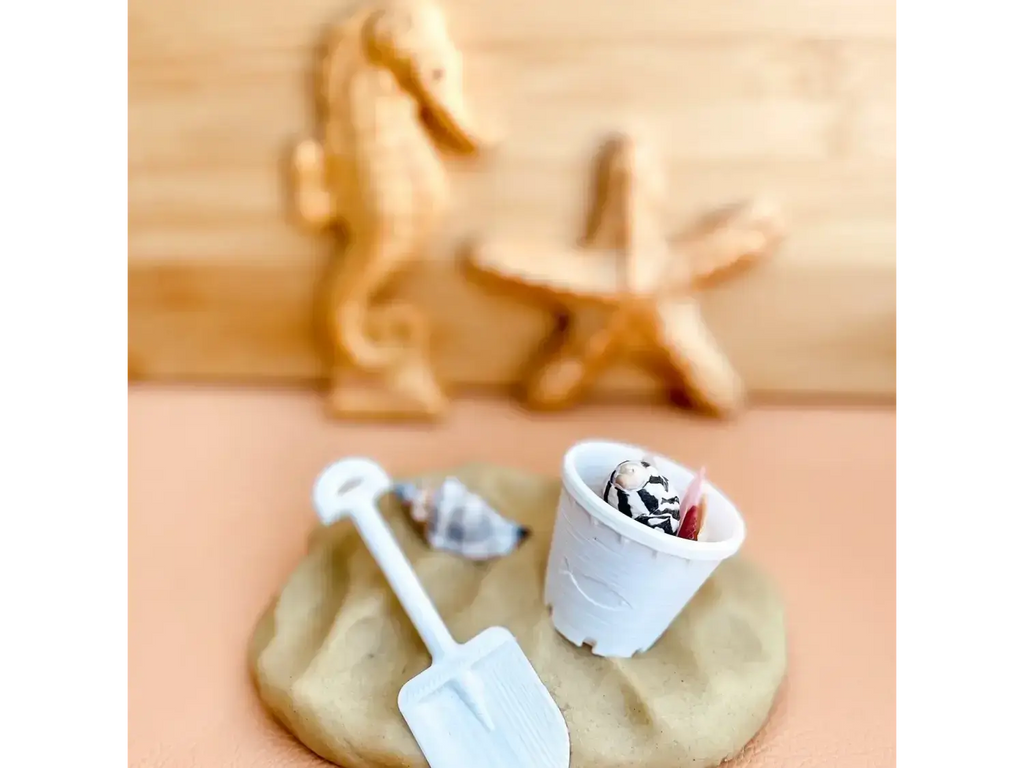 Sand-colored play dough with miniature beach-themed toys and accessories.
