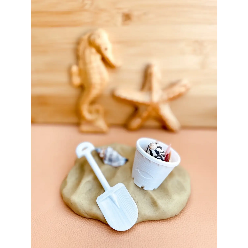 Sand-colored play dough with miniature beach-themed toys and accessories.