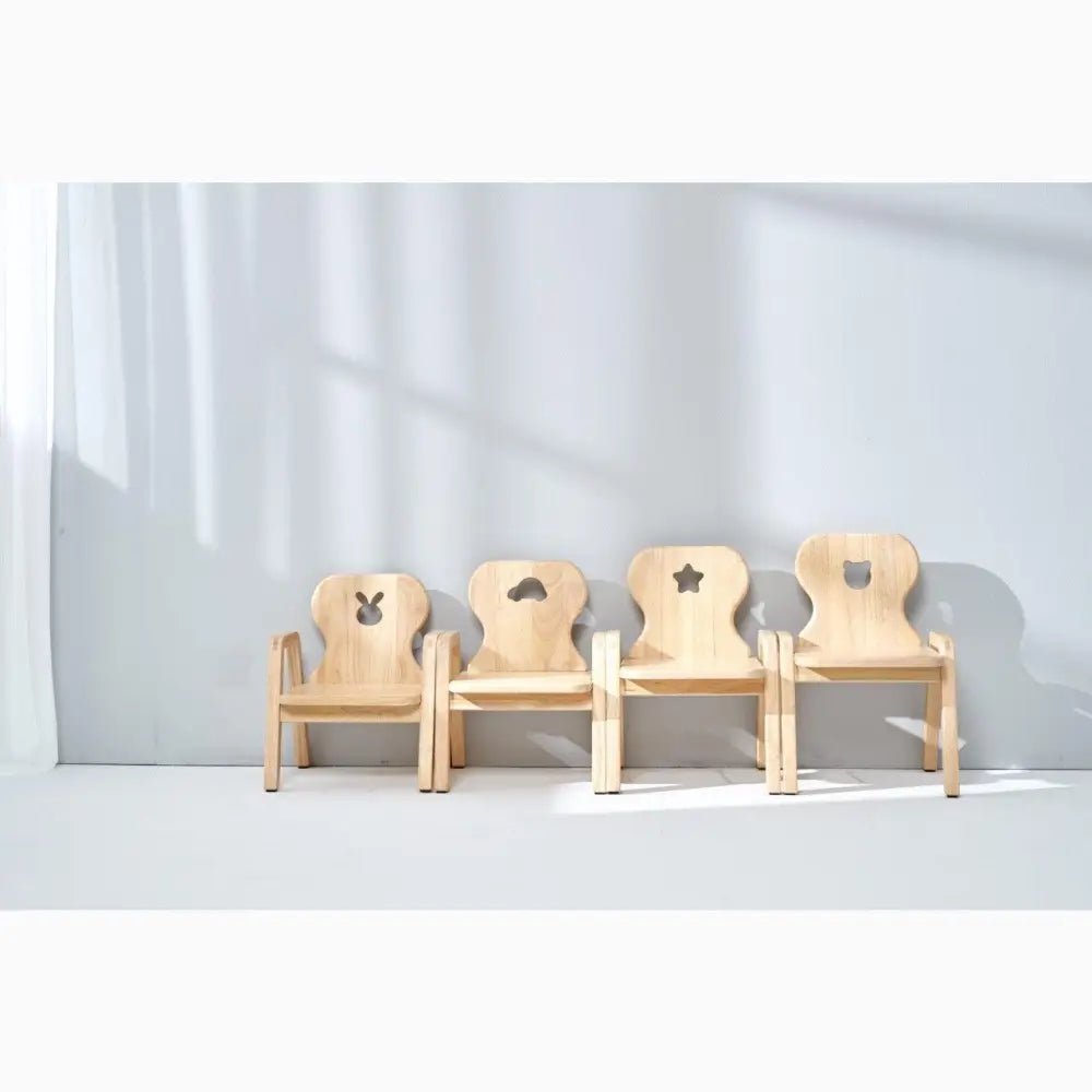 Four wooden children’s chairs with different cutout shapes in their backrests.