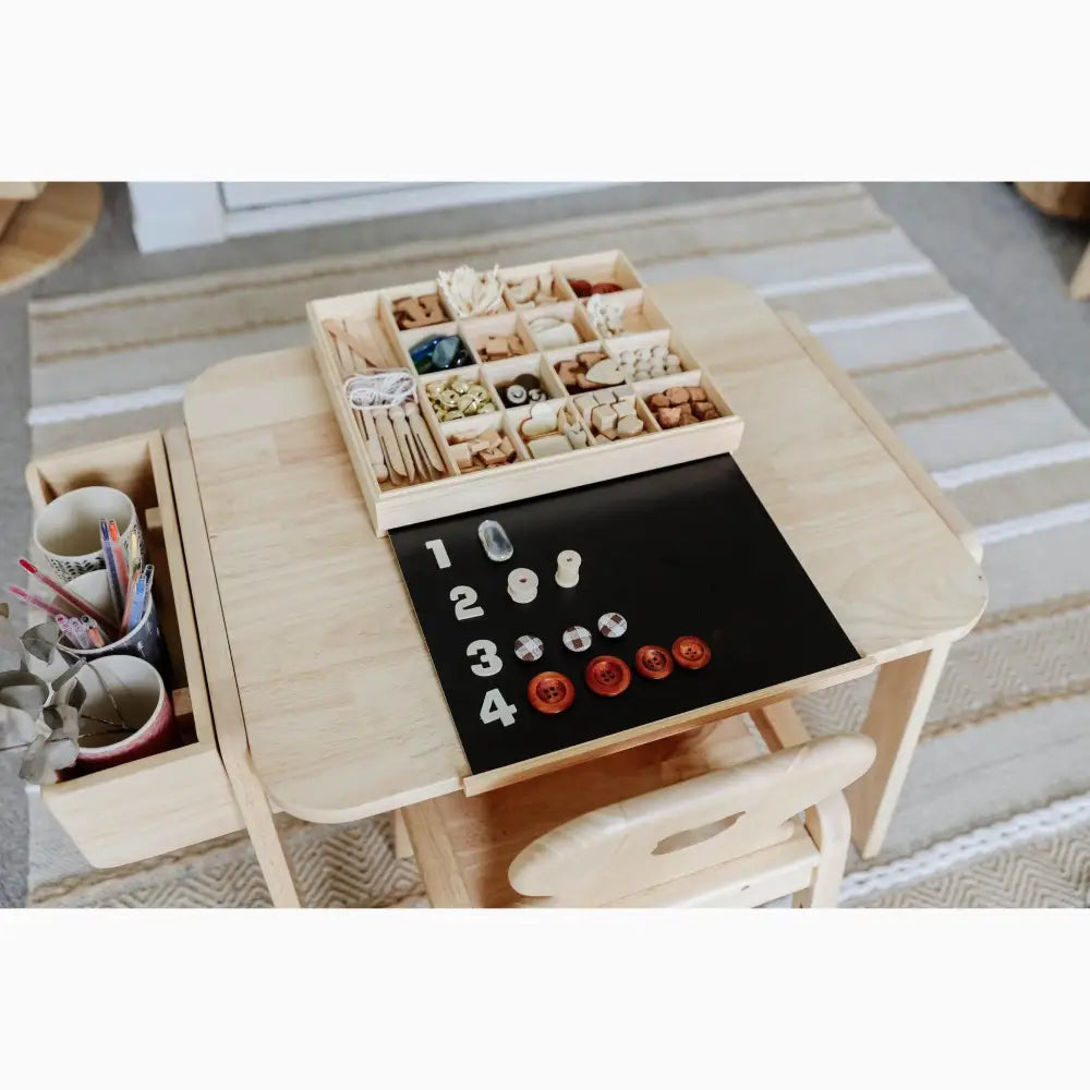 Wooden table with compartments for organizing small objects and a black surface for counting or learning activities.