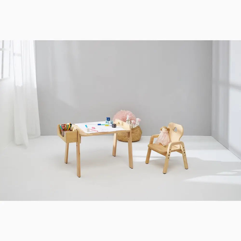 Wooden children’s desk and chair set with art supplies on the tabletop.