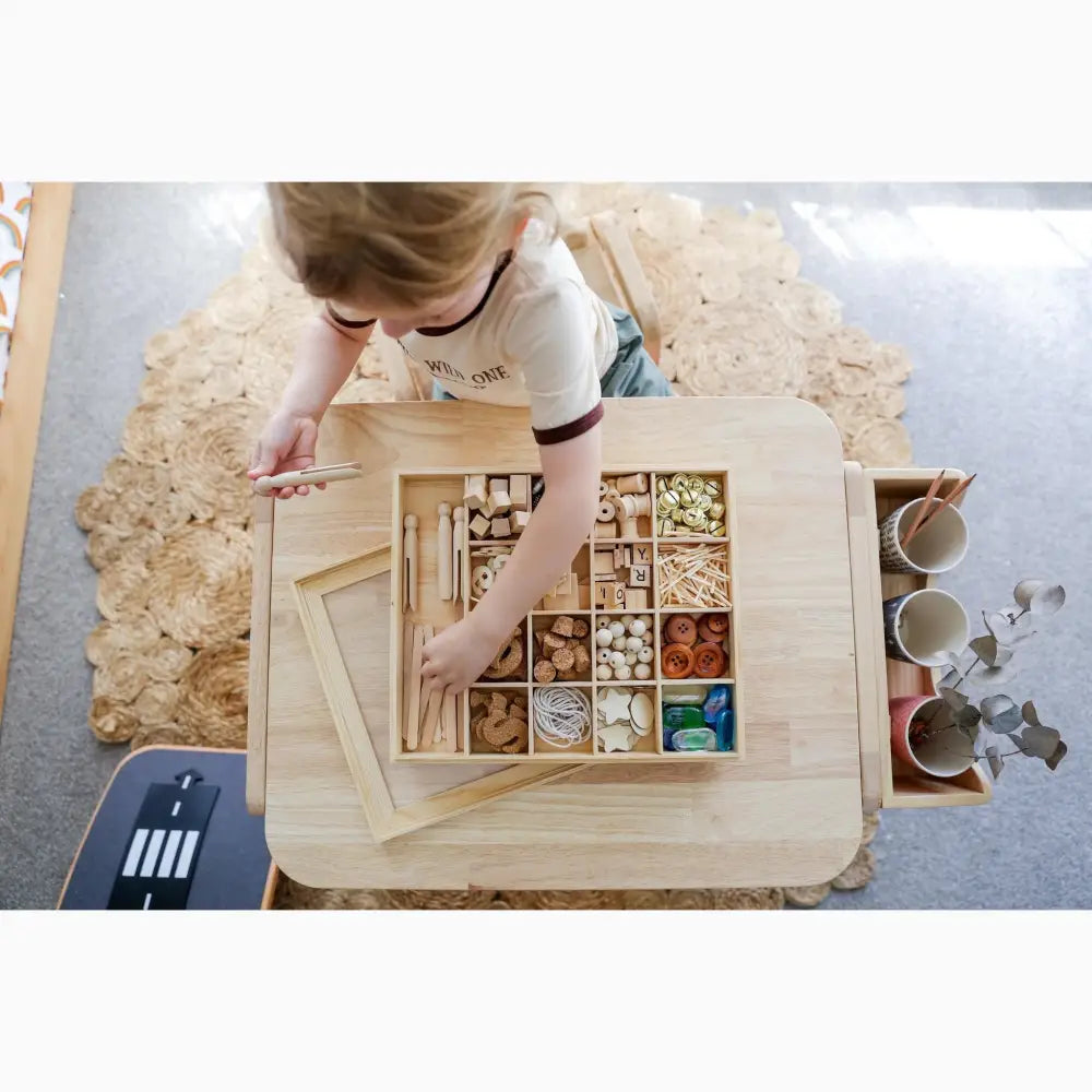 Wooden box with compartments containing various small objects and materials.