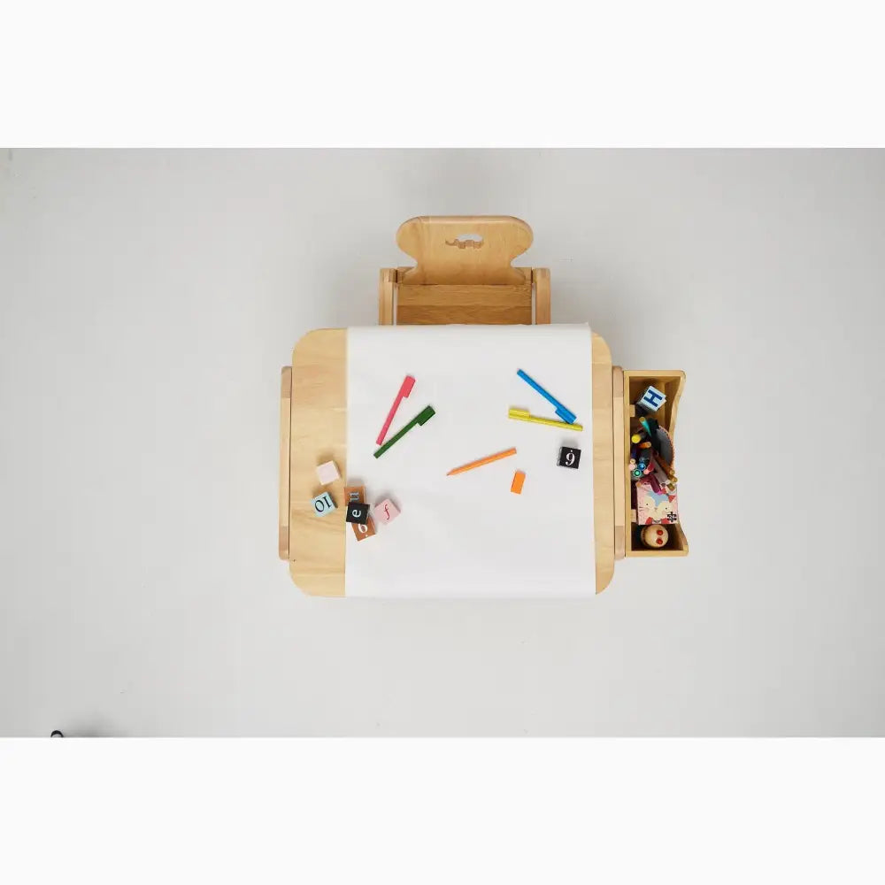 Wooden children’s desk with attached chair and storage compartments, featuring a white drawing surface and colorful art supplies.