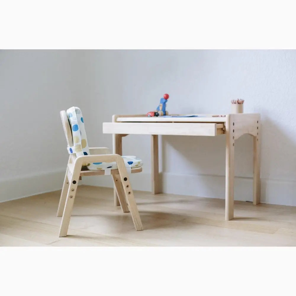 Children’s desk and chair set made of light-colored wood with colorful accents.