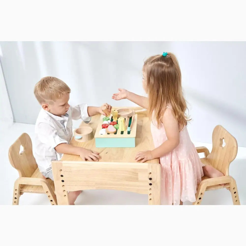 Wooden children’s table with two chairs and a colorful toy on top.