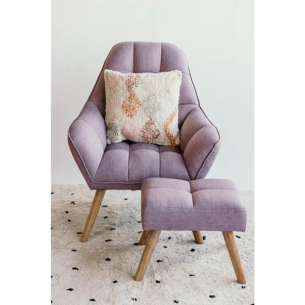 Lavender-colored armchair with matching footstool and decorative pillow.