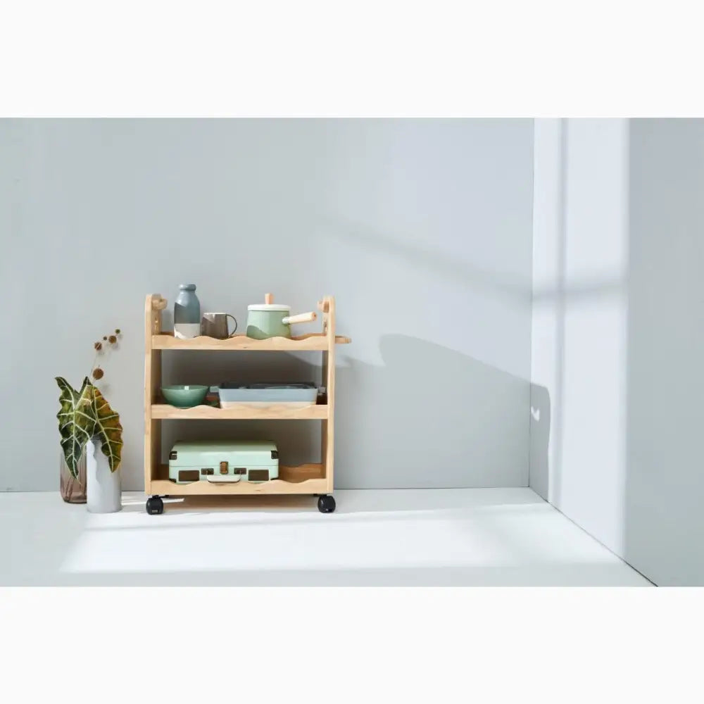 Wooden rolling cart with three shelves holding various household items.