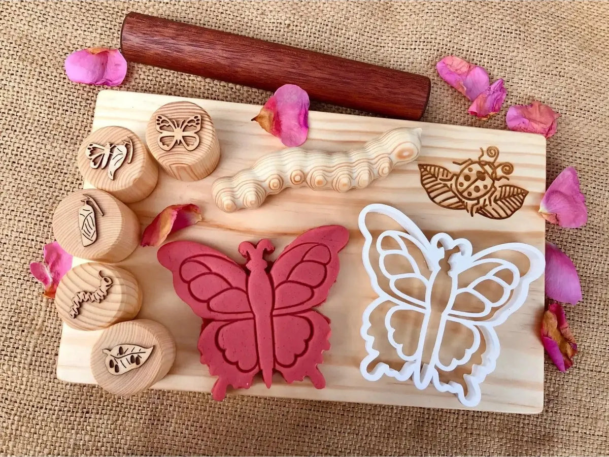 Wooden board with butterfly-themed stamps, cookie cutters, and a rolling pin.