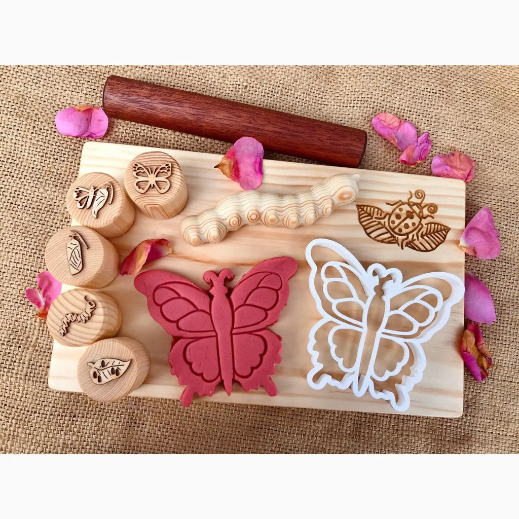 Wooden board with butterfly-themed stamps, cookie cutters, and a rolling pin.