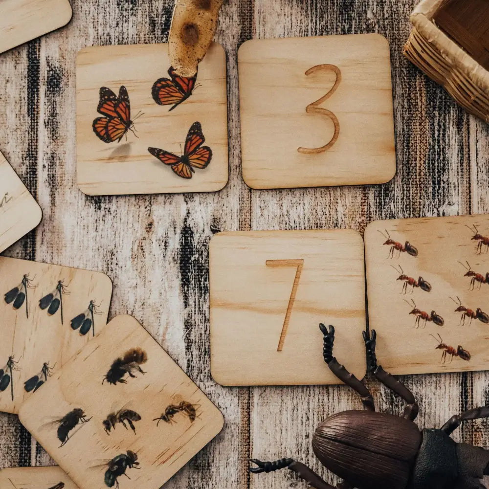 Wooden number and insect tiles arranged on a textured surface.