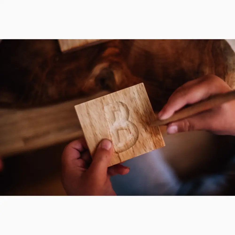 Wooden block with the letter ’B’ carved or engraved into it.