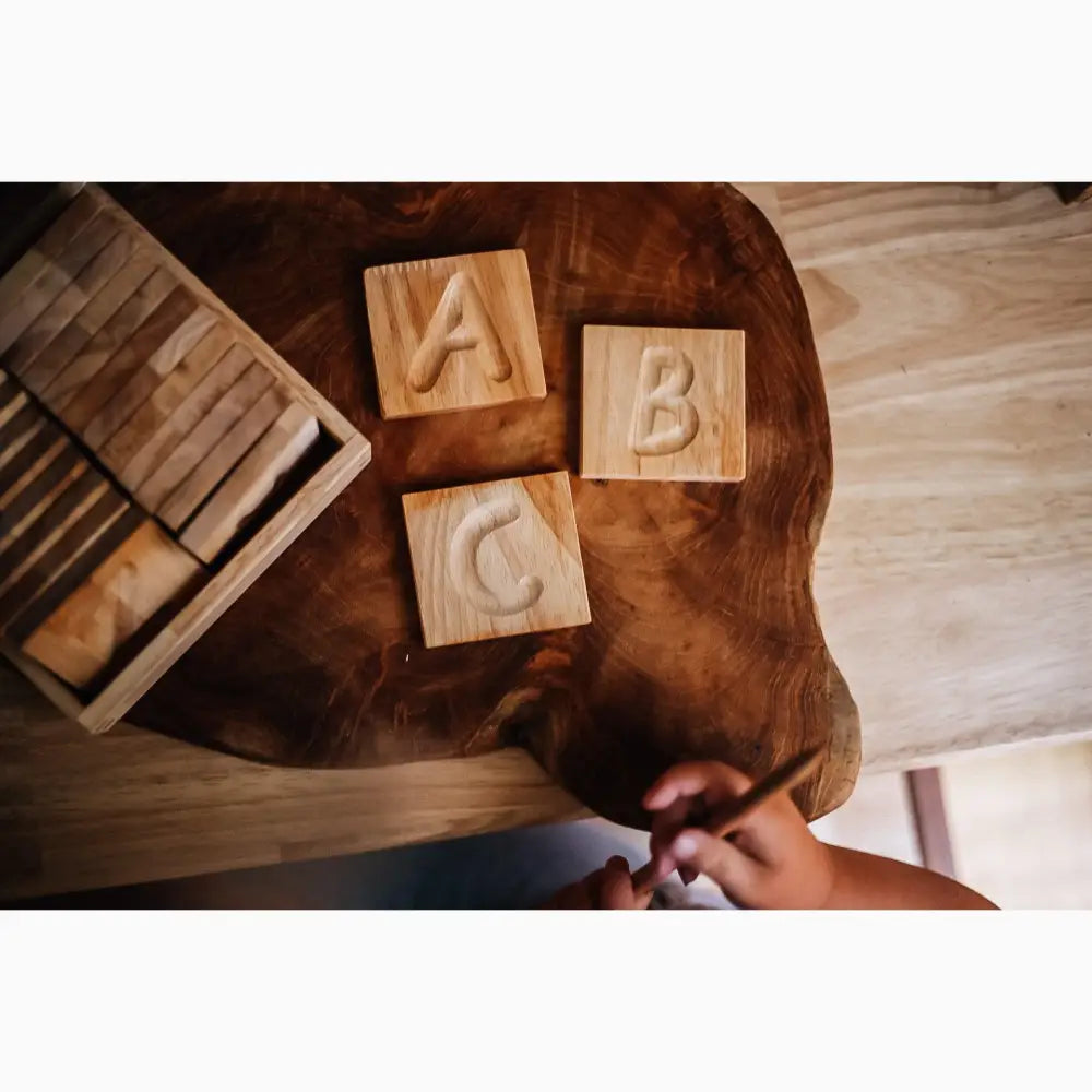 Wooden alphabet blocks displaying letters A, B, and C on a table surface.