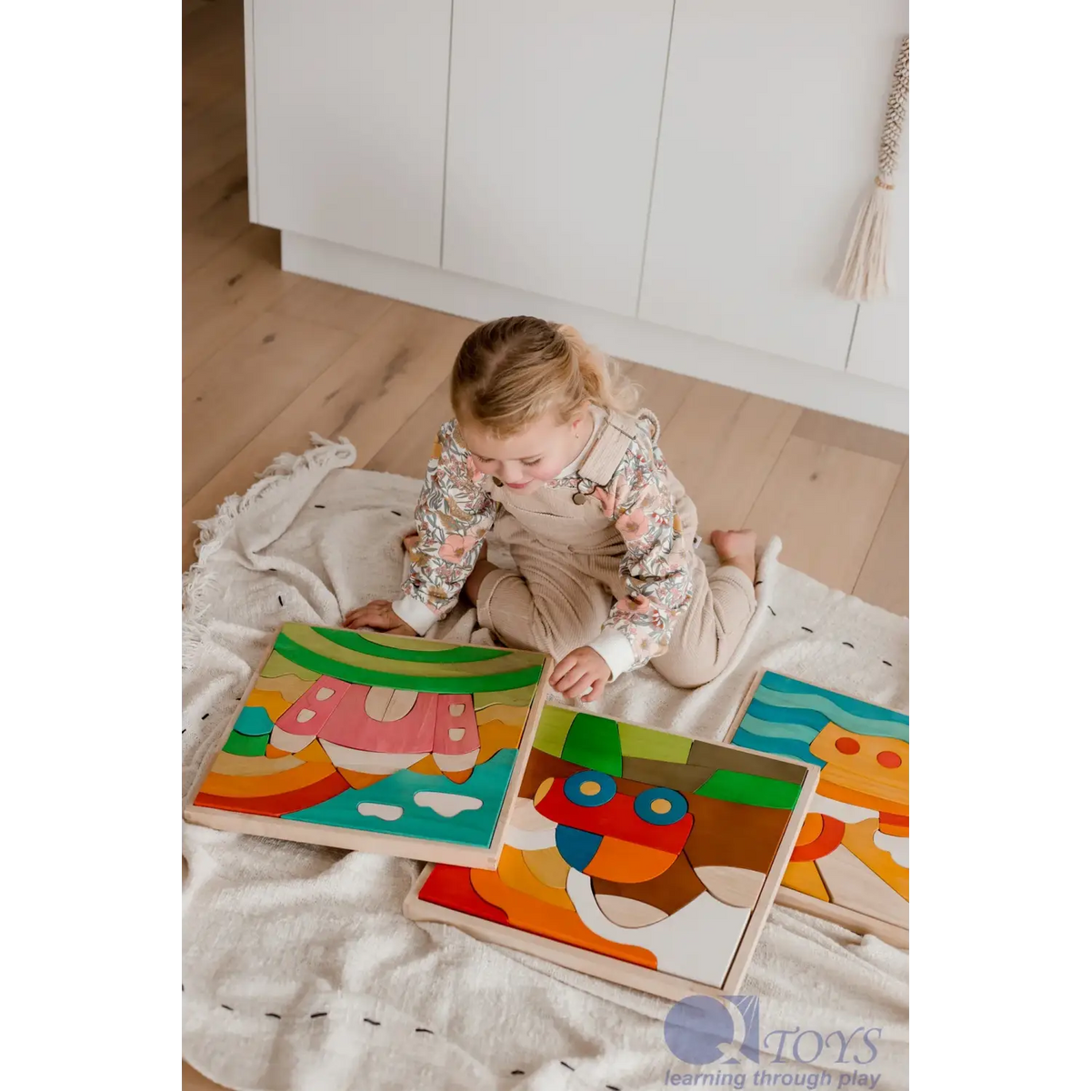 Toddler playing with colorful wooden puzzle pieces on a blanket.