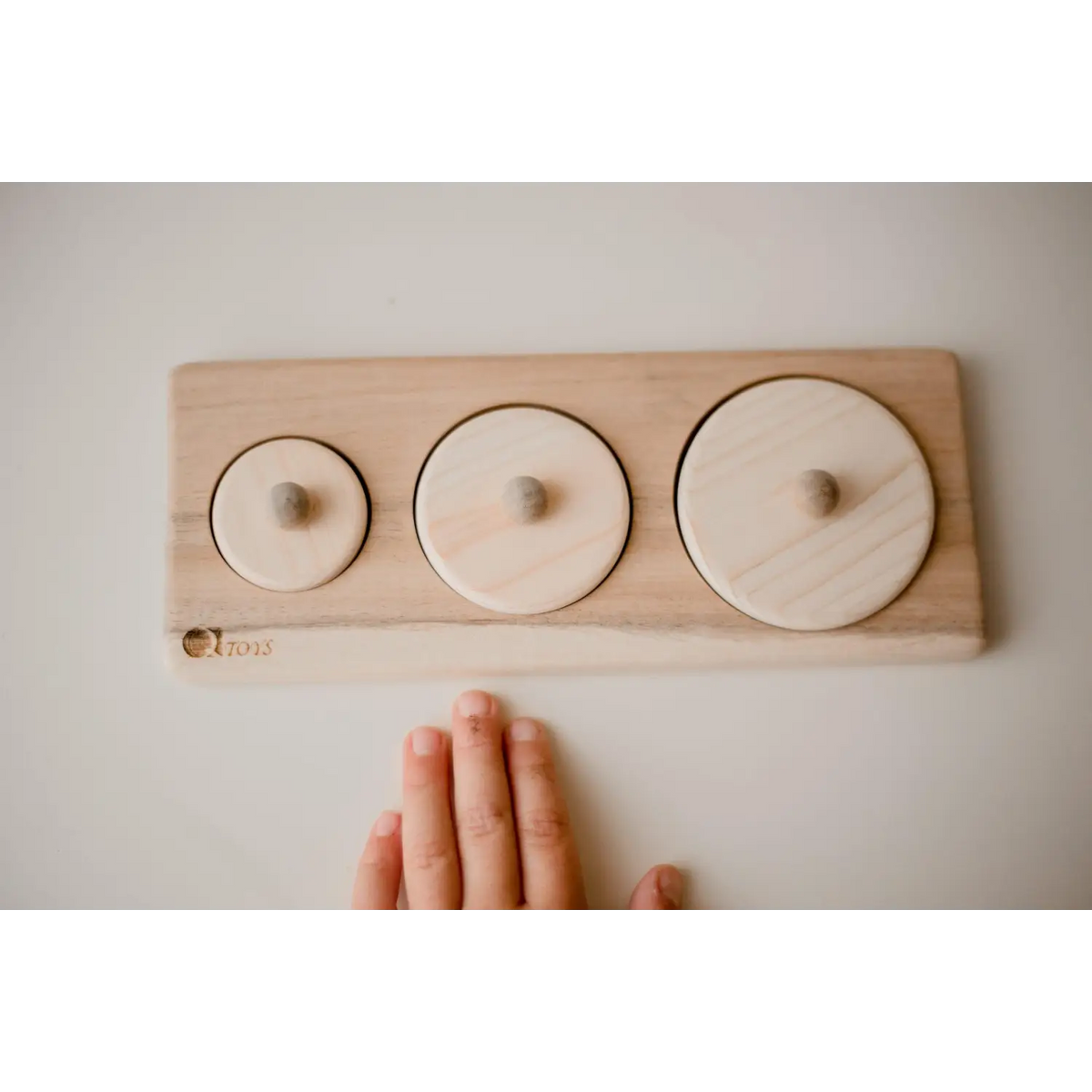 Wooden puzzle board with three circular pieces of increasing size.