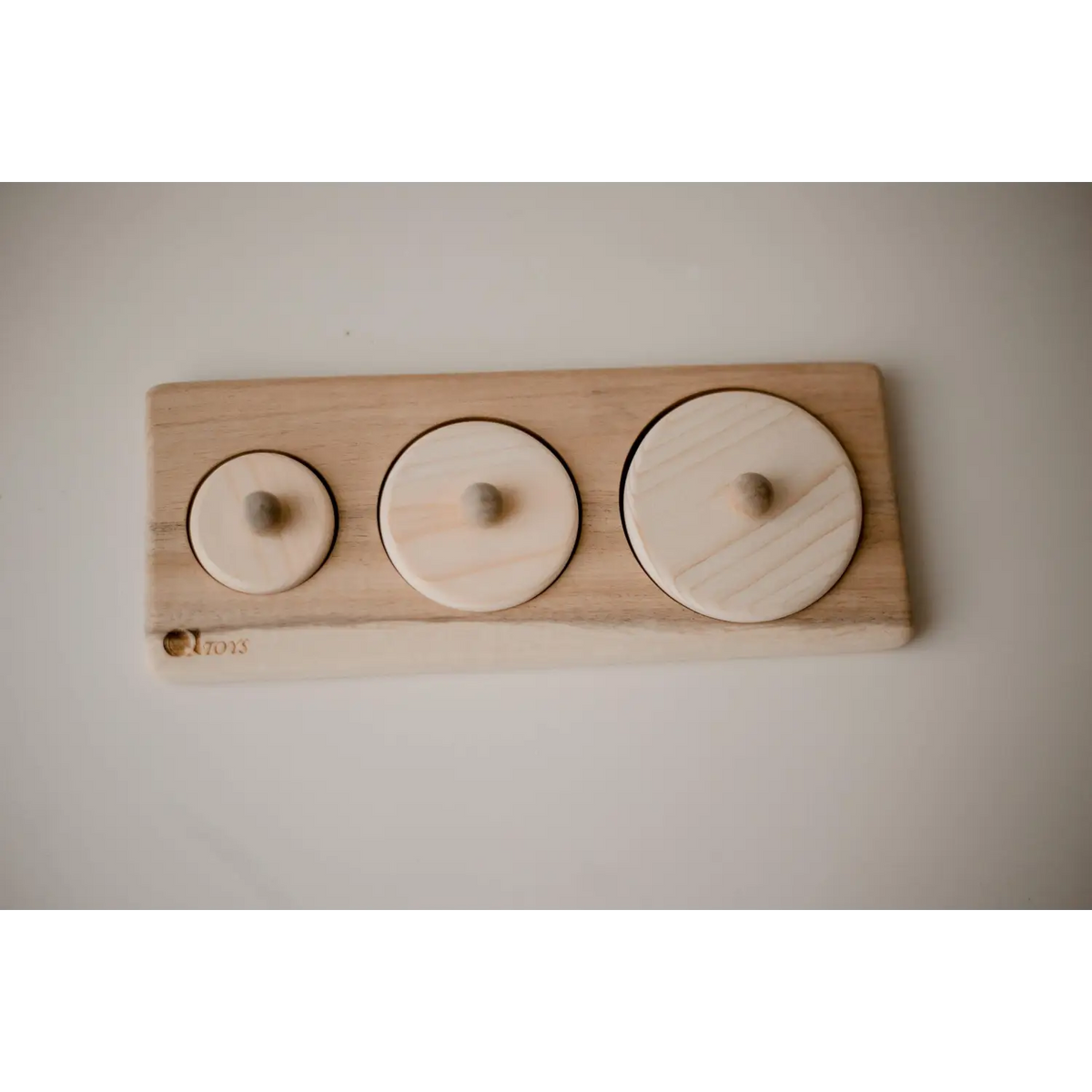 Wooden board with three circular indentations of varying sizes.