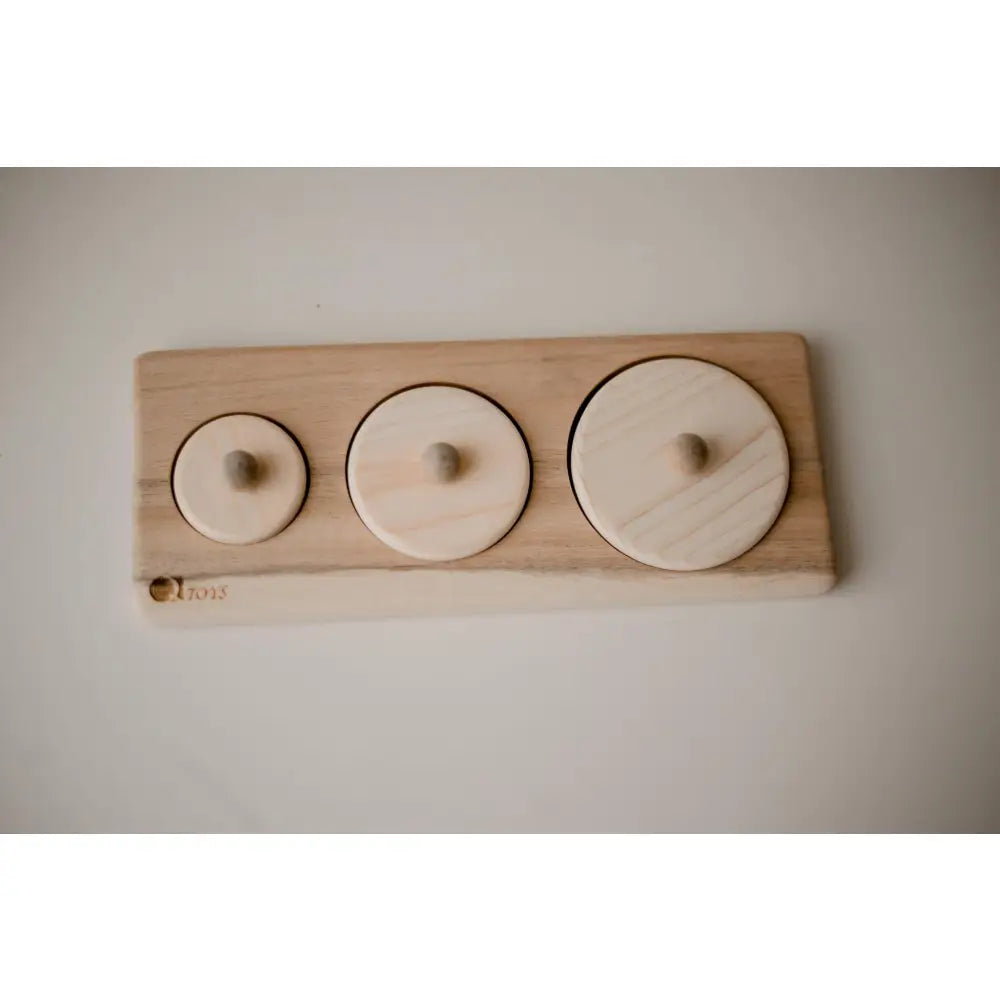 Wooden board with three circular indentations of varying sizes.