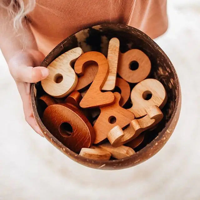 Wooden number toys in a coconut shell bowl.