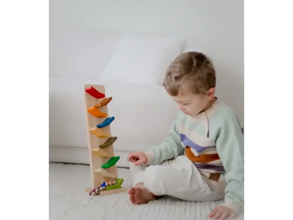 Young child playing with a colorful wooden toy track.