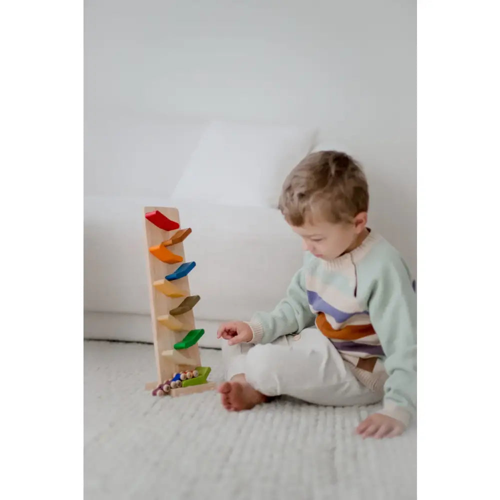 Young child playing with a colorful wooden toy track.