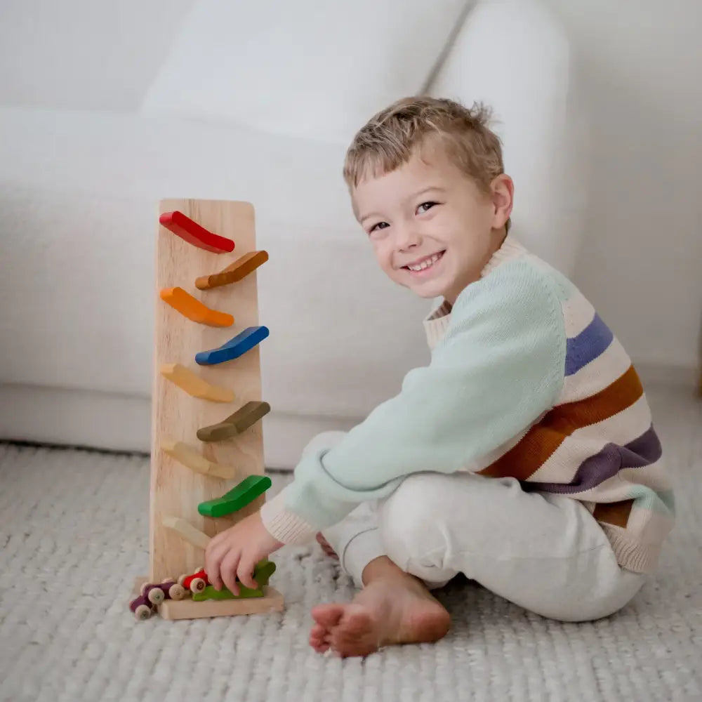 Smiling young child sitting on a carpet with a wooden toy.