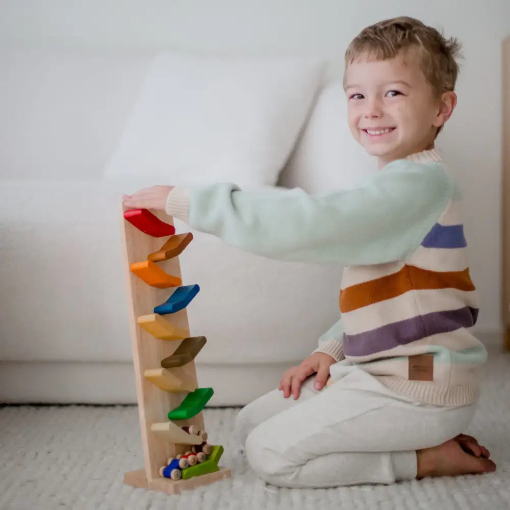 Smiling child playing with a colorful wooden stacking toy.