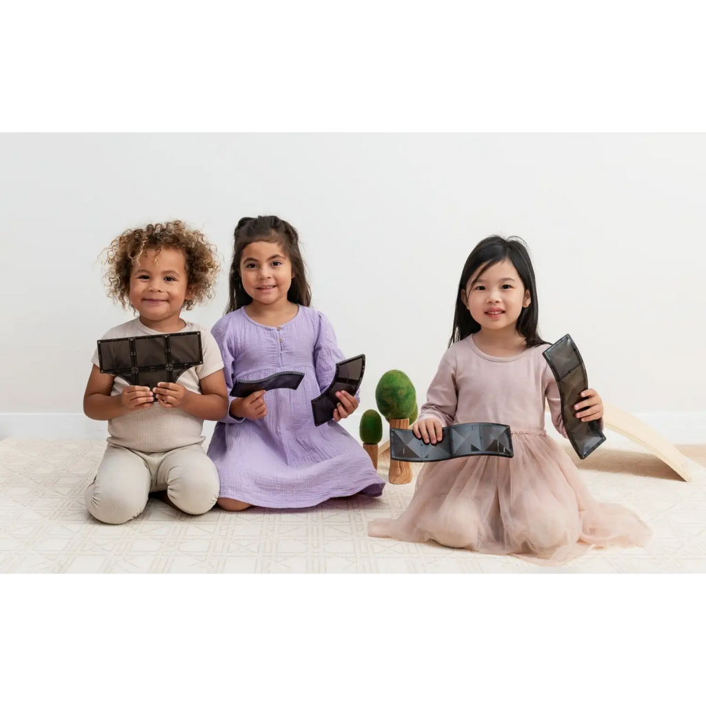 Three young girls sitting on the floor holding electronic tablets.