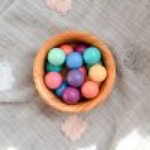 Bowl filled with colorful round objects, likely candies or small balls.