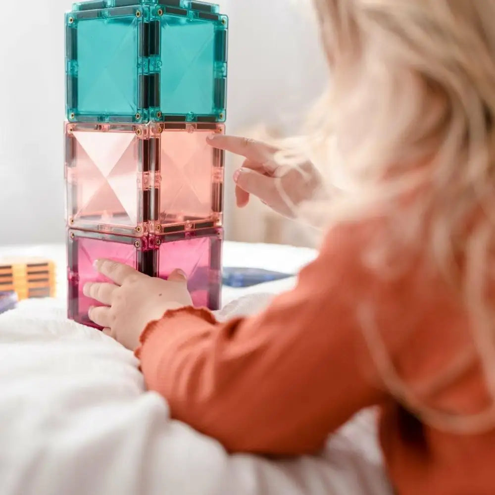 Colorful stacked magnetic building tiles being played with by small hands.