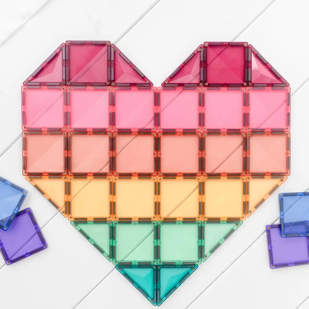 Heart-shaped arrangement of colorful, translucent geometric tiles in rainbow order.