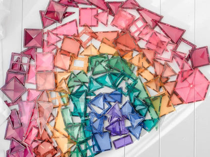 Rainbow-colored arrangement of square paper pieces forming a fan or arc shape.
