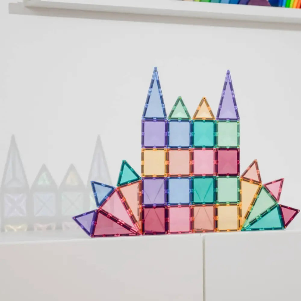 Colorful geometric construction made of translucent magnetic tiles arranged in a castle-like shape.