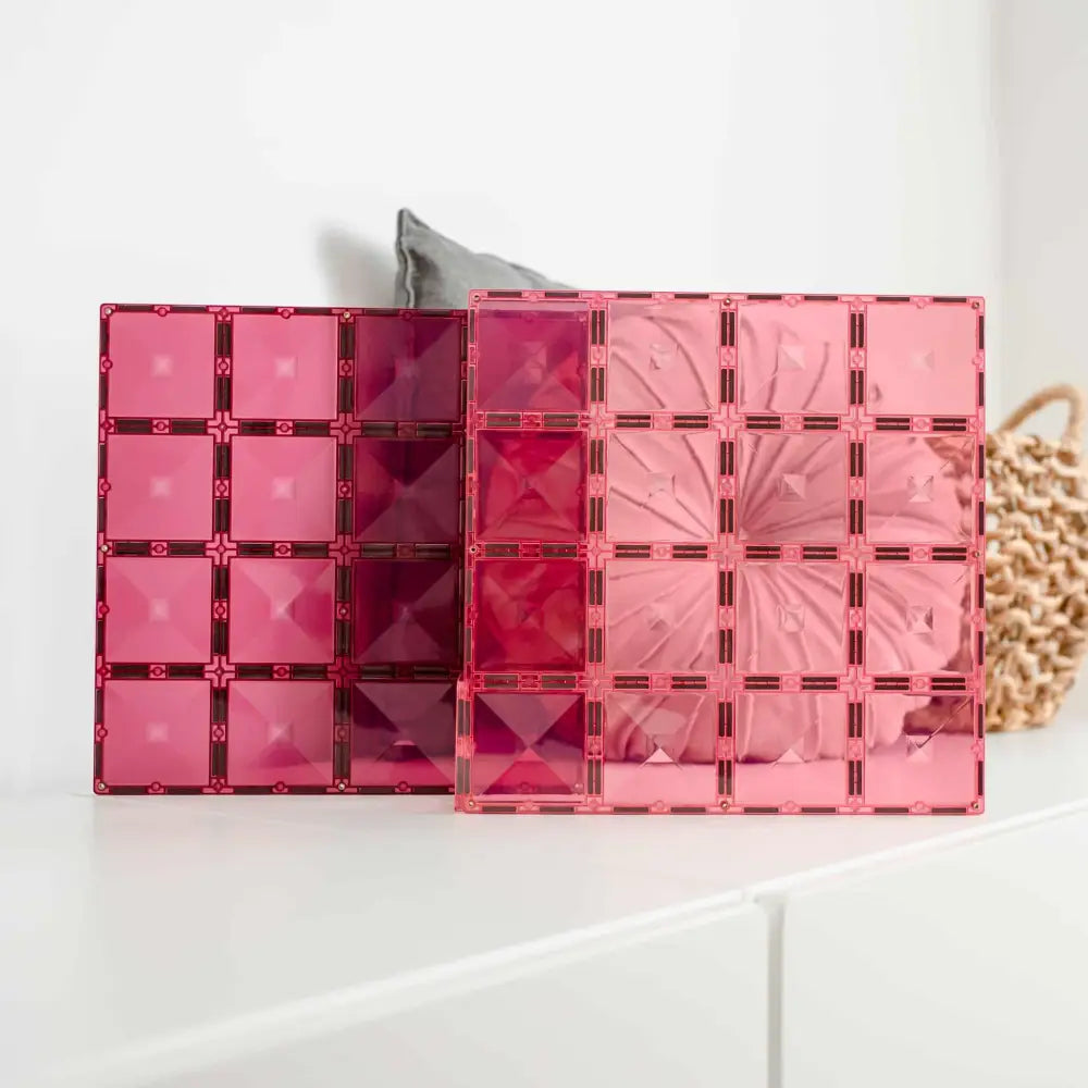 Set of pink and red transparent acrylic or plastic storage organizers with grid patterns.