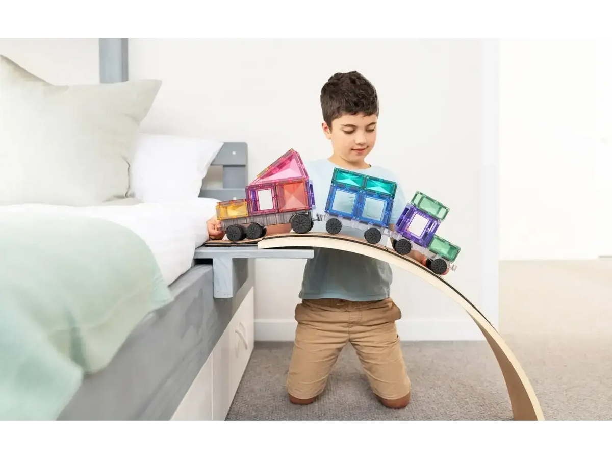 Child rolling a Connetix Pastel Transport Pack train along a wooden arch