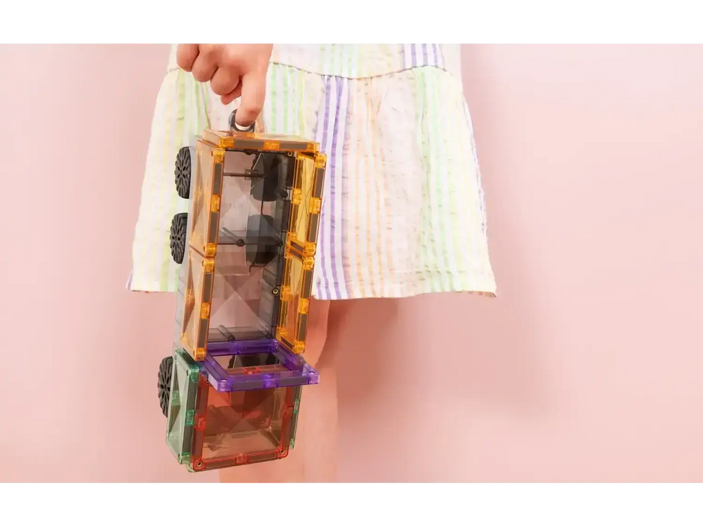 Colorful magnetic building tiles held by a hand against a pastel background.