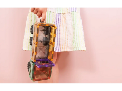 Colorful magnetic building tiles held by a hand against a pastel background.