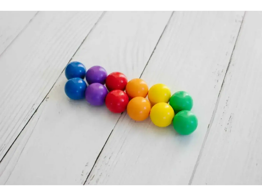 Colorful gumballs arranged in a triangular shape on a wooden surface.