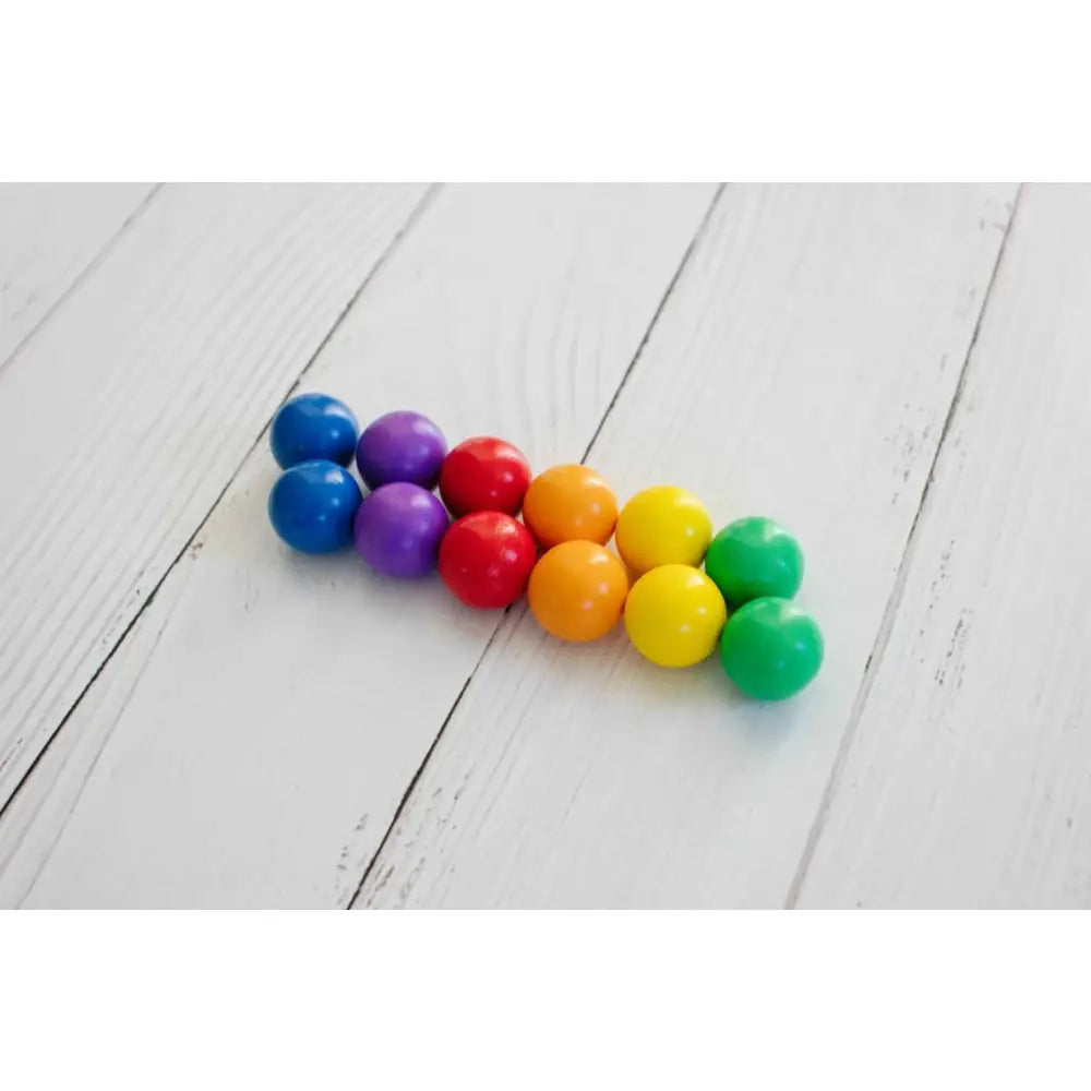 Colorful gumballs arranged in a triangular shape on a wooden surface.