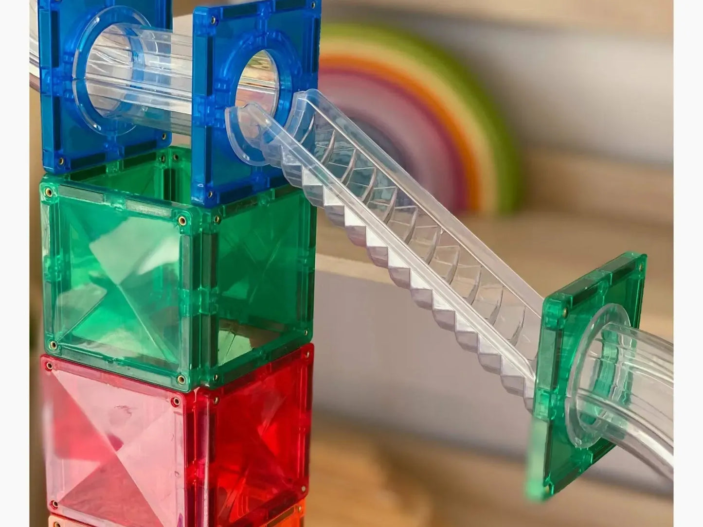 Colorful plastic building blocks with a transparent tube and staircase attachment.