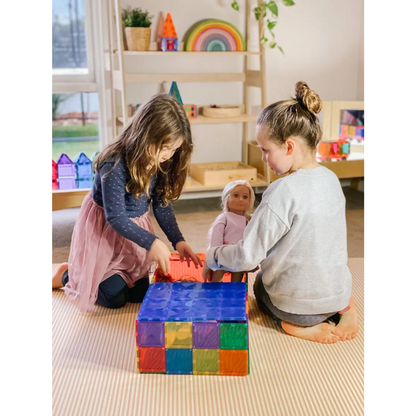 Two children playing with colorful building blocks on a carpeted floor.