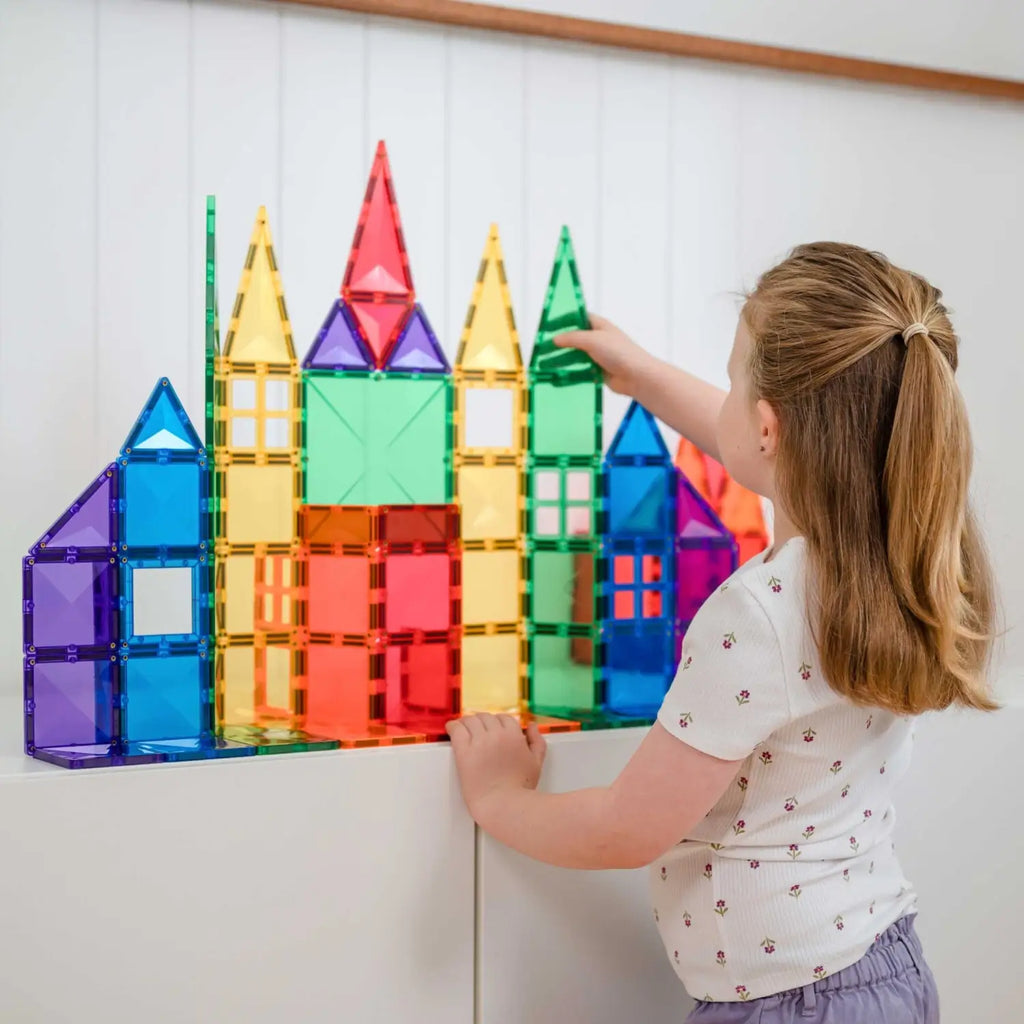 Colorful magnetic building tiles arranged into a castle-like structure on a wall.