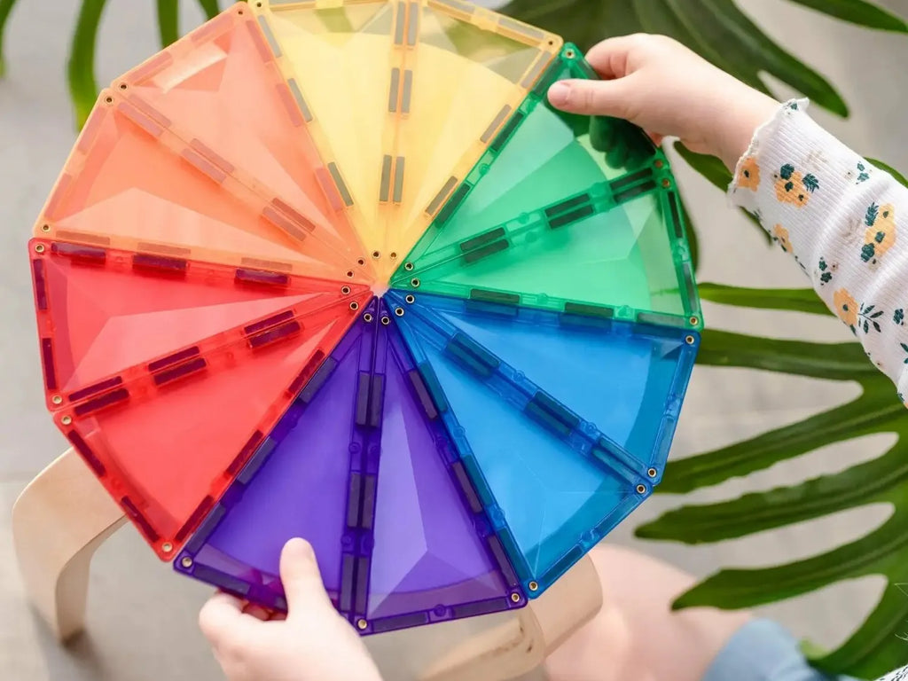 Colorful circular wheel divided into rainbow-hued segments held by hands.