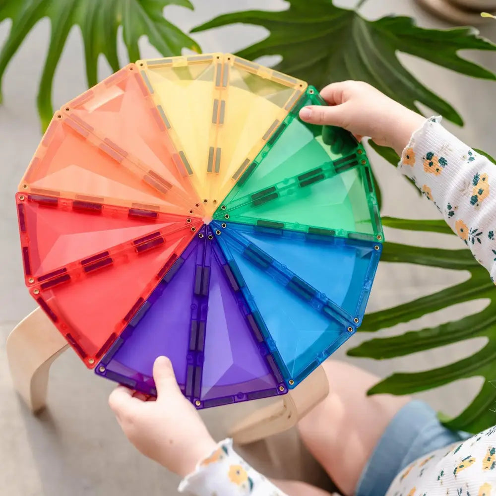 Colorful circular wheel divided into rainbow-hued segments held by hands.