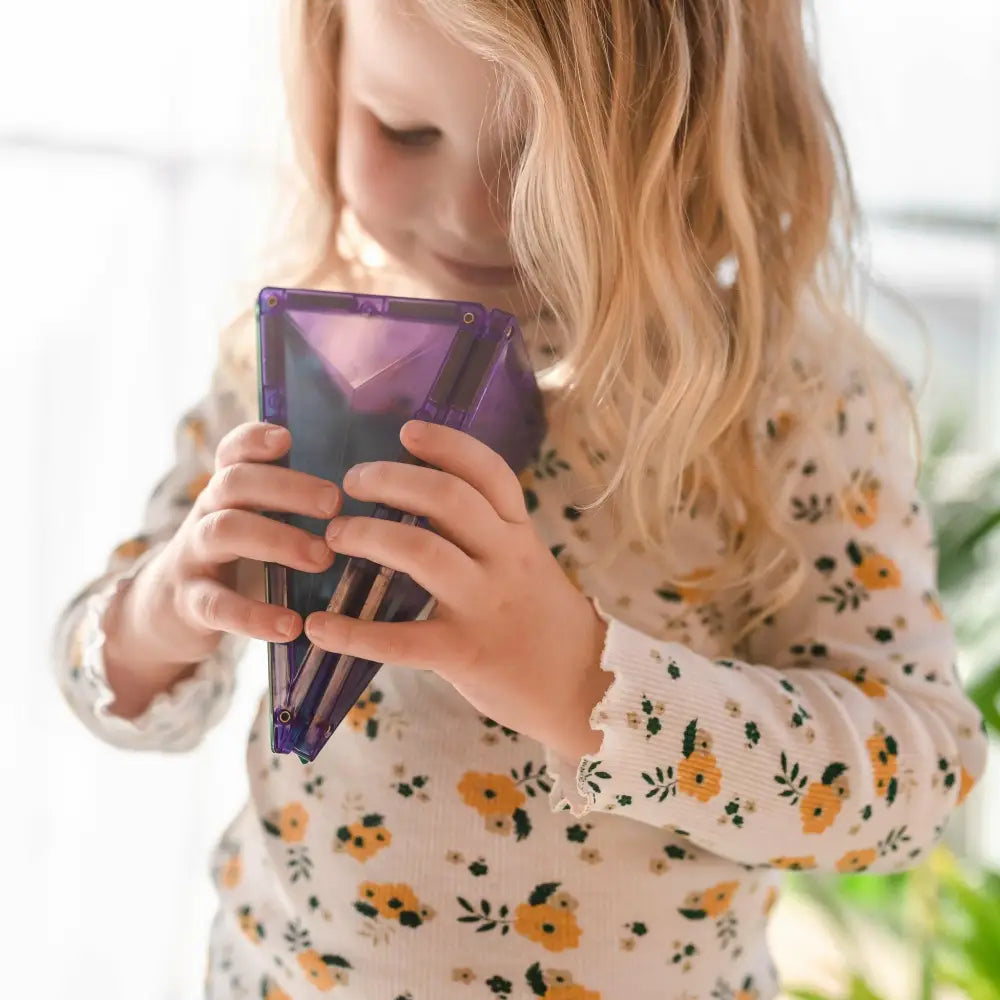 Purple tablet or e-reader device held by hands in a floral-patterned sleeve.